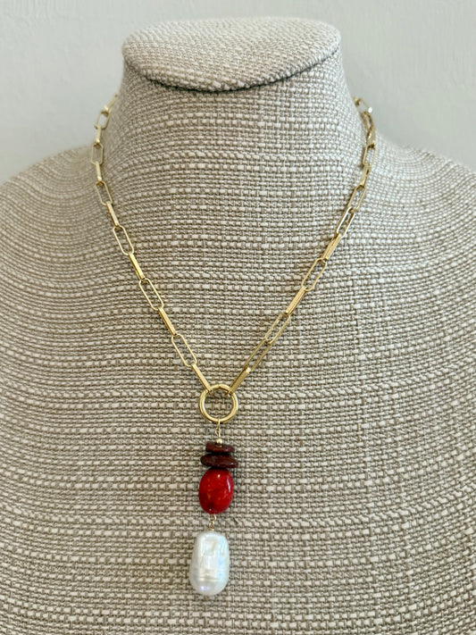 Necklace with a red pendant and pearl on a mannequin bust.