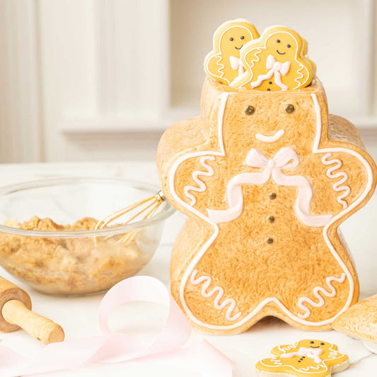 Decorative gingerbread man cookie with smaller cookies on top, surrounded by baking ingredients.