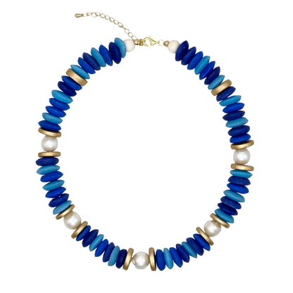 Necklace with blue, gold, and white beads on a beige fabric background