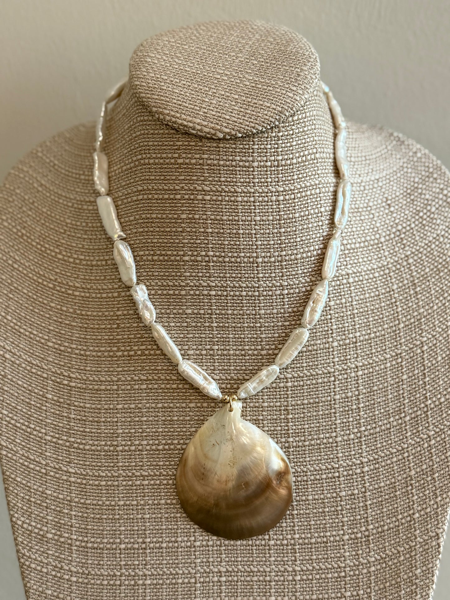 Necklace with a large pearl  shell pendant on a mannequin bust.