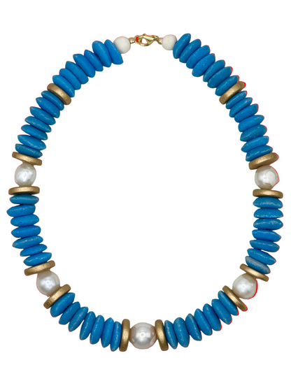 Necklace with blue beads, gold accents, and pearls on a beige fabric background