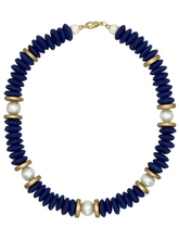 Load image into Gallery viewer, Necklace with blue beads, gold accents, and pearls on a beige fabric background