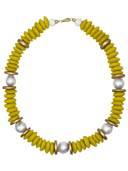 Necklace with yellow, gold, and pearl beads on a light fabric background