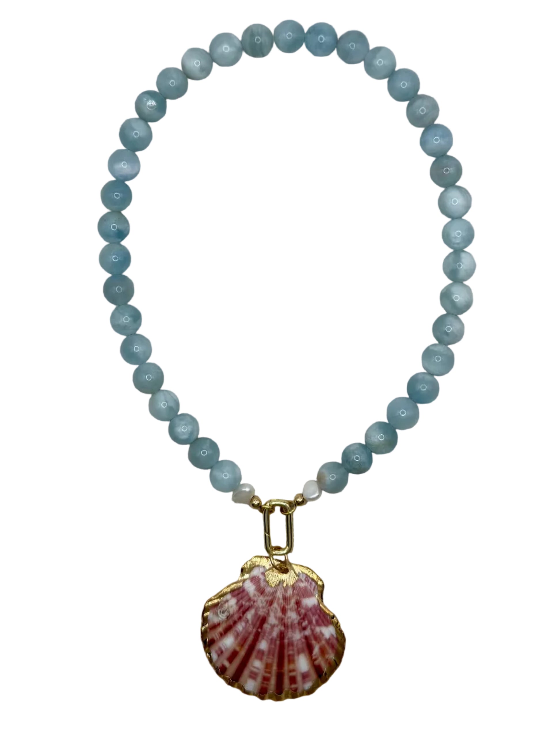 A beaded necklace featuring light blue faceted beads and a pink and white seashell pendant with gold-tone trim, displayed on a textured beige fabric background.