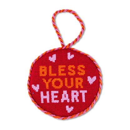 Circular red embroidered ornament with 'Bless Your Heart' text and heart designs on a white background