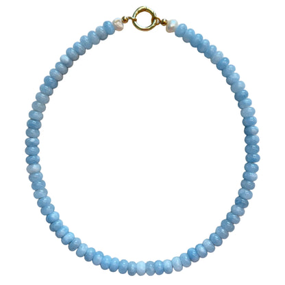 Blue beaded necklace with a gold clasp on a beige fabric background